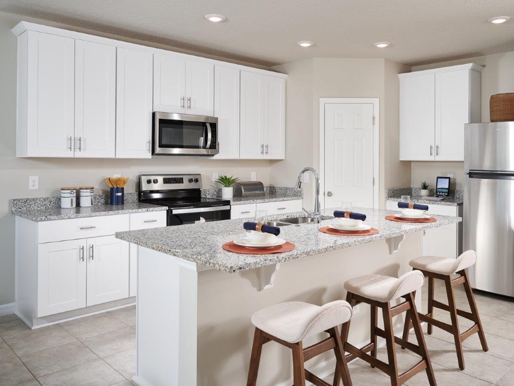 a kitchen with stainless steel appliances kitchen island granite countertop a sink a stove a table and chairs