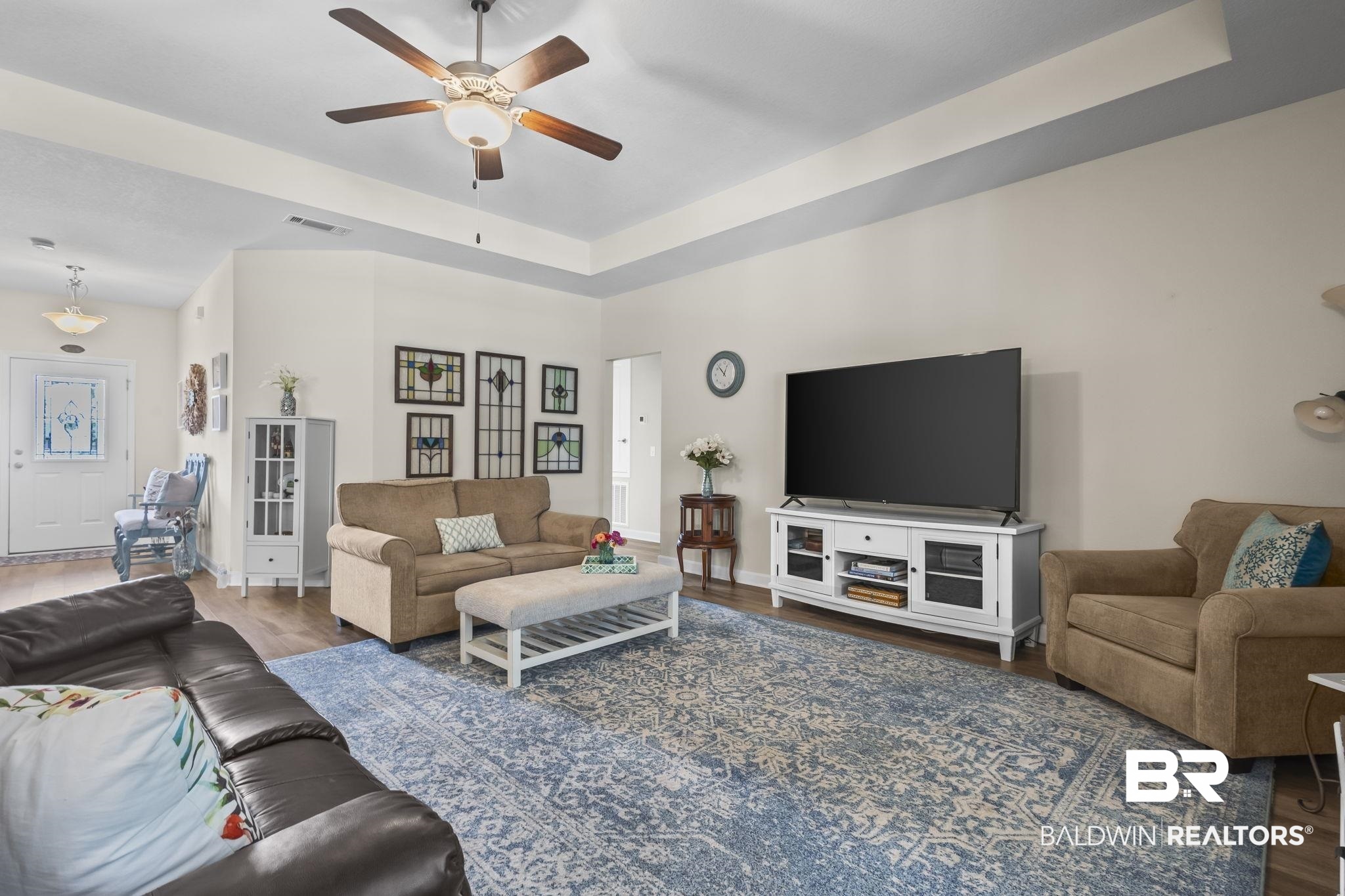 10473 Lyttleton Loop Lillian, AL 36549 - Photo 9 of 57 Living area featuring wood finished floors, ceiling fan, and a tray ceiling
