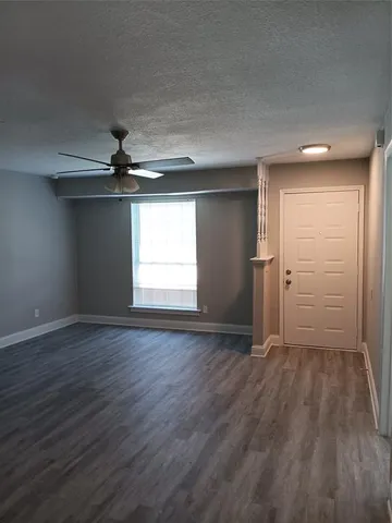 an empty room with wooden floor cabinet and windows