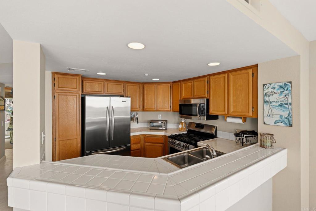 400 The Strand North, Unit 7 Oceanside, CA 92054 - Photo 12 of 35 a room with stainless steel appliances a refrigerator a sink a stove a counter top space and a window