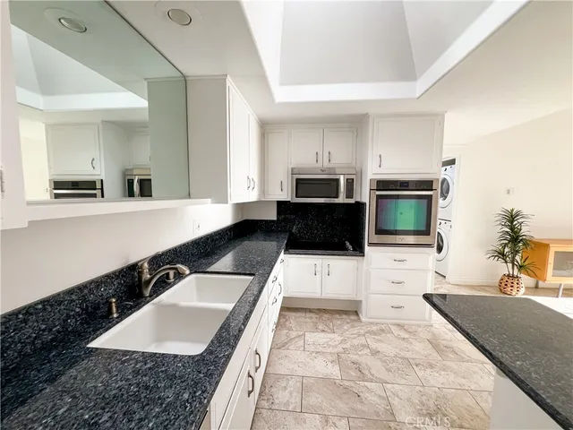 a large kitchen with kitchen island granite countertop a sink and white cabinets