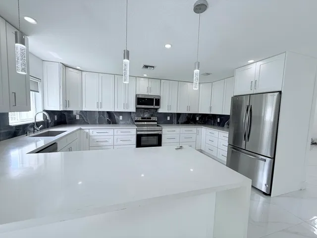 a kitchen with a refrigerator a sink and white cabinets