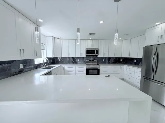 a large kitchen with kitchen island a sink stainless steel appliances and white cabinets