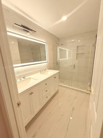 a bathroom with a double vanity sink a mirror and a shower
