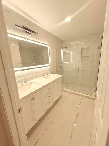 a bathroom with a double vanity sink a mirror and a shower