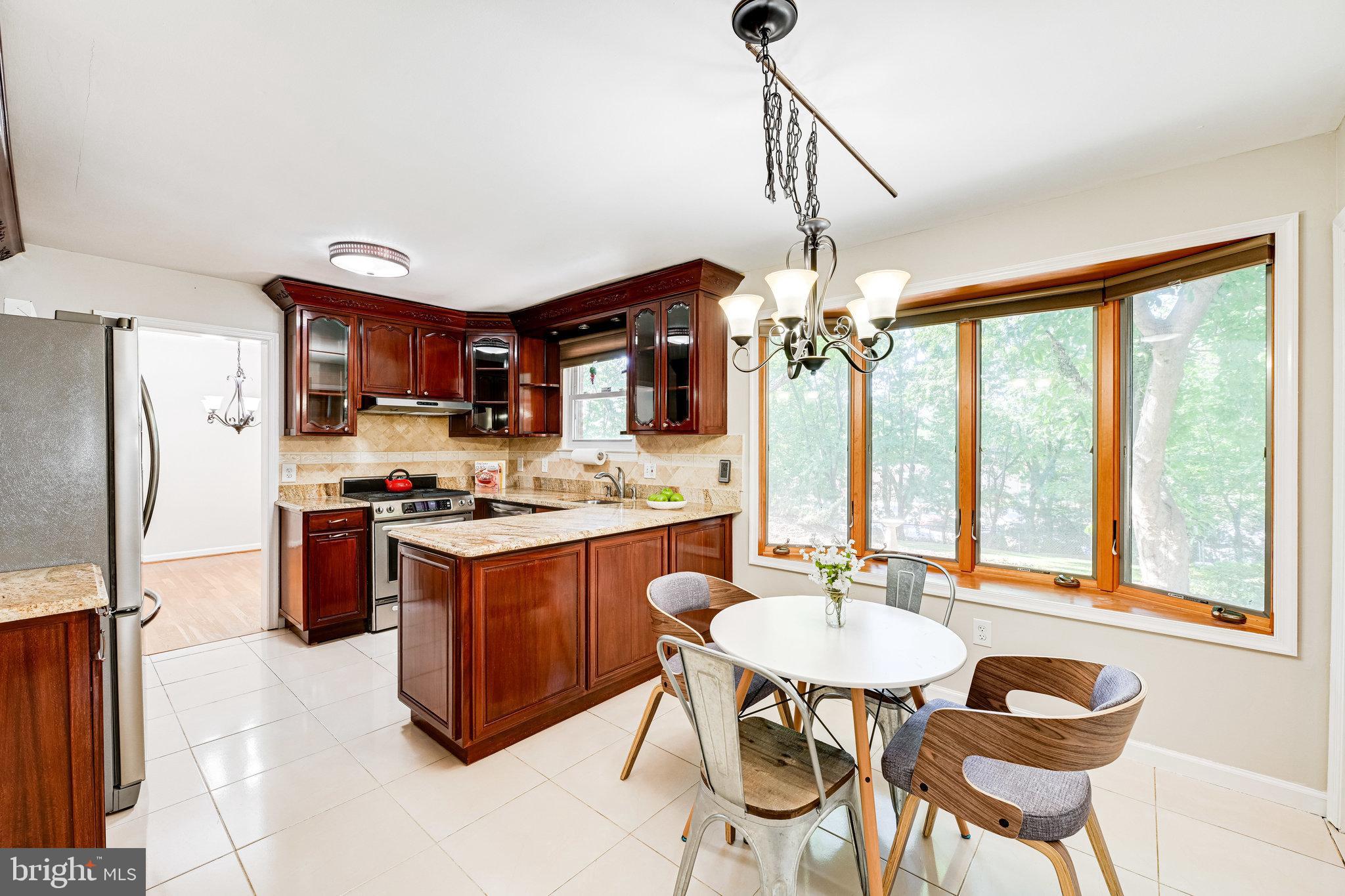 a kitchen with stainless steel appliances granite countertop a kitchen island hardwood floor sink stove dining table and chairs