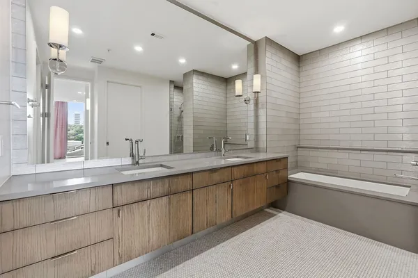 a bathroom with a double vanity sink mirror and a bathtub