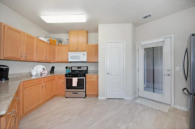a large kitchen with stainless steel appliances granite countertop a stove and a refrigerator