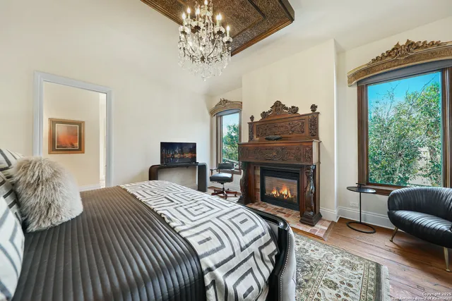 a bedroom with a bed a chandelier and a fireplace
