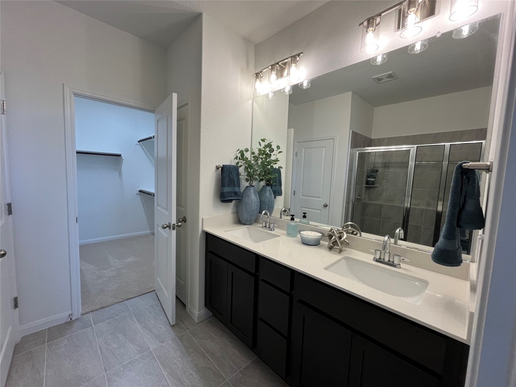 8506 Wellspring Loop Round Rock, TX 78665 - Photo 9 of 33 Bathroom with double vanity, a spacious closet, and a stall shower