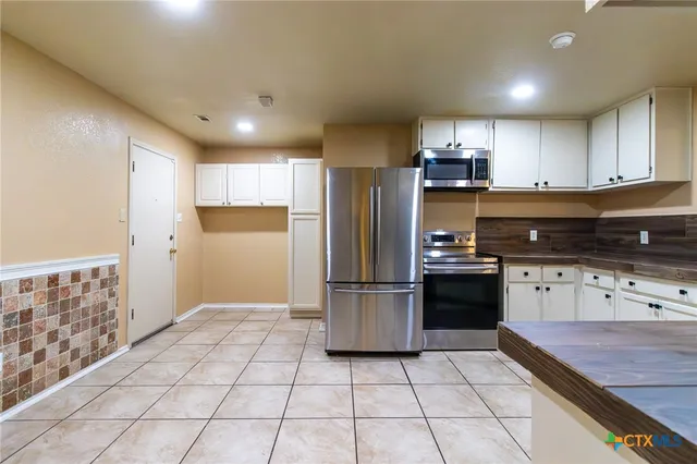 a kitchen with stainless steel appliances granite countertop a refrigerator and a stove top oven