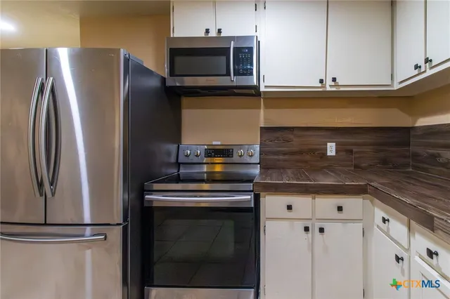 a kitchen with stainless steel appliances white cabinets and a refrigerator