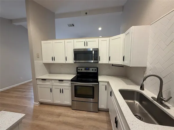 a kitchen with a sink a stove and cabinets