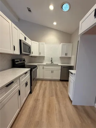 a large kitchen with stainless steel appliances granite countertop a stove a sink dishwasher and a refrigerator