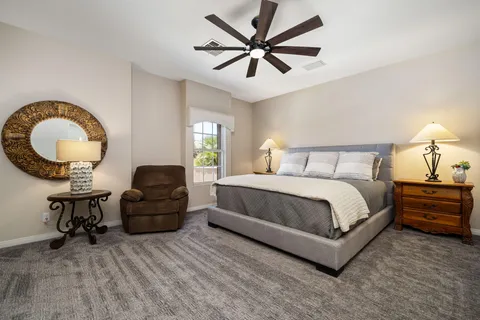 a spacious bedroom with a bed a mirror and a large window