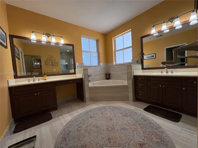 a spacious bathroom with a tub sink and mirror