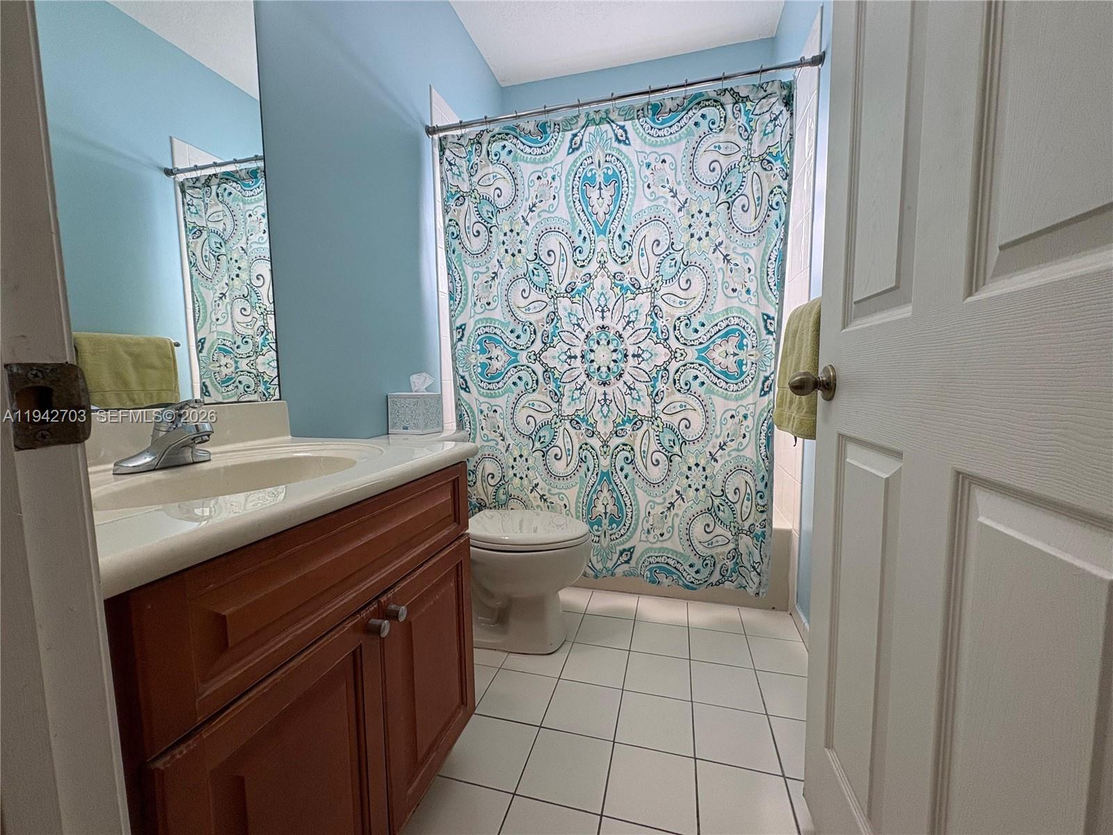 5902 Southwest 166th Court Miami, FL 33193 - Photo 19 of 27 a bathroom with a sink a toilet and shower curtain