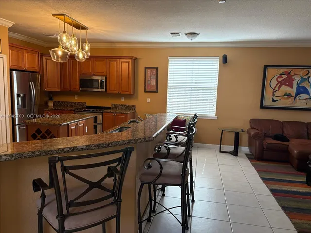 a kitchen with stainless steel appliances granite countertop a sink a stove a refrigerator cabinets and dining table