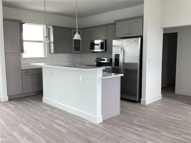 a kitchen with kitchen island a counter top space wooden floor and a window