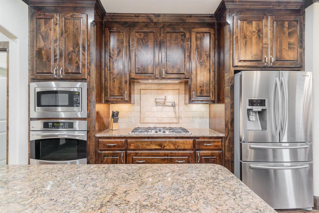 289 Blackjack Road Valley View, TX 76272 - Photo 21 of 40 a kitchen with granite countertop stainless steel appliances and wooden cabinets