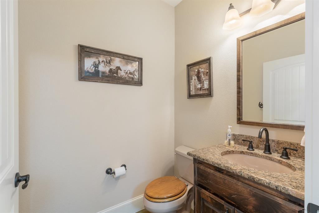 289 Blackjack Road Valley View, TX 76272 - Photo 27 of 40 a bathroom with a granite countertop toilet a sink and mirror