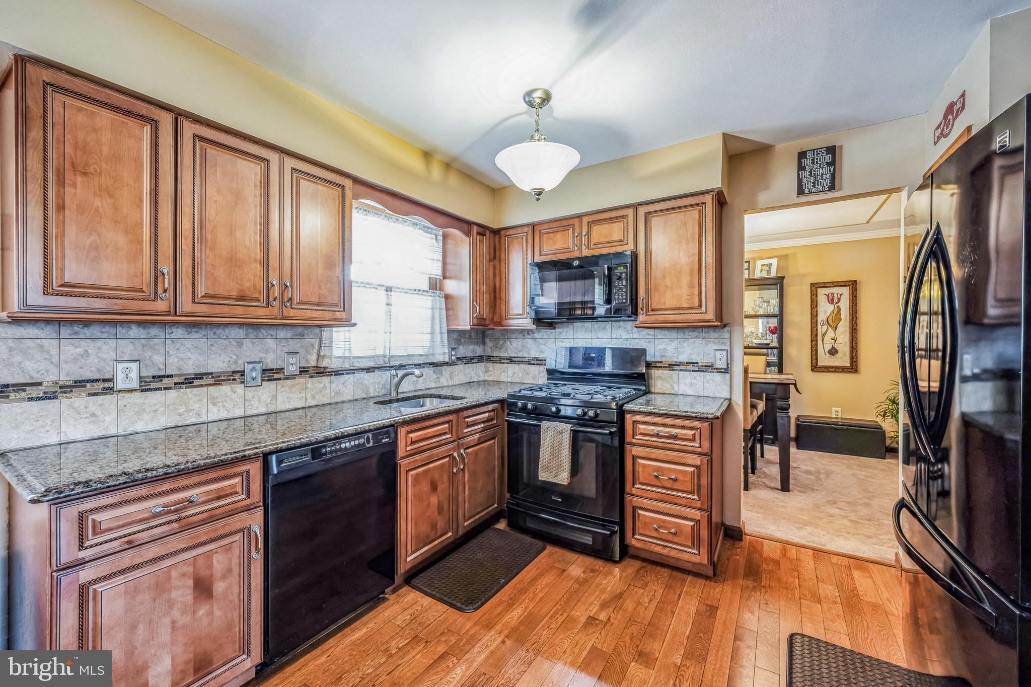 415 Doerrmann Drive Mickleton, NJ 08056 - Photo 12 of 38 a kitchen with stainless steel appliances granite countertop a stove top oven a sink dishwasher a dining table and chairs with wooden floor