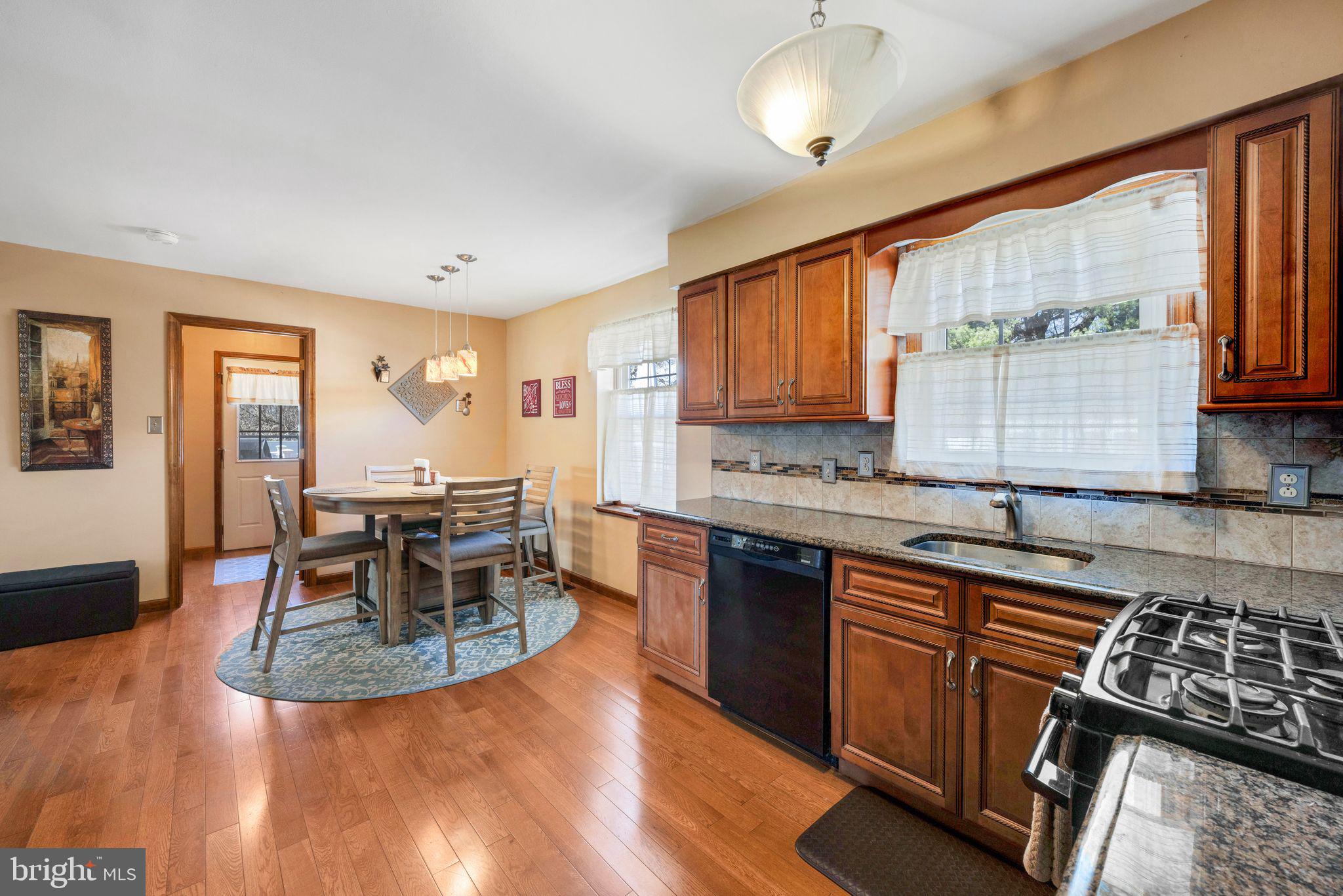 415 Doerrmann Drive Mickleton, NJ 08056 - Photo 13 of 38 a kitchen with stainless steel appliances granite countertop a stove top oven a sink a dining table and chairs with wooden floor
