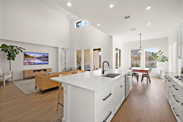 a large white kitchen with a large window and stainless steel appliances