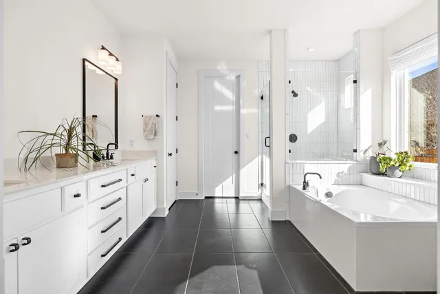 a spacious bathroom with double vanity a mirror a bathtub and a shower