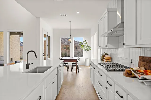a kitchen that has a lot of cabinets a sink and appliances in it