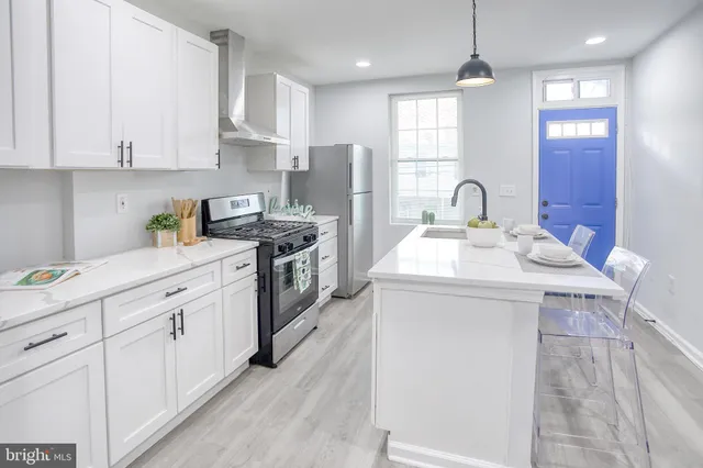 a kitchen with stainless steel appliances granite countertop a sink stove refrigerator and white cabinets with wooden floor