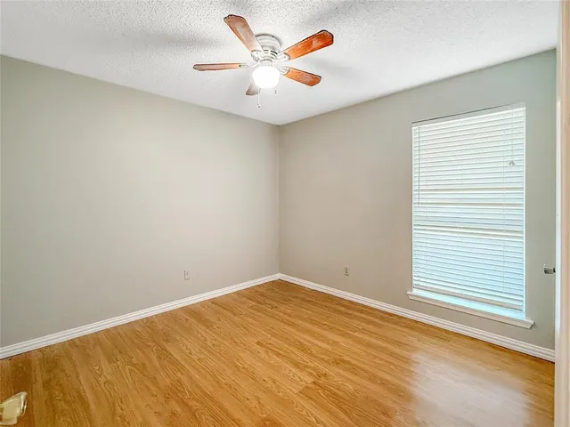 an empty room with a window and a ceiling fan