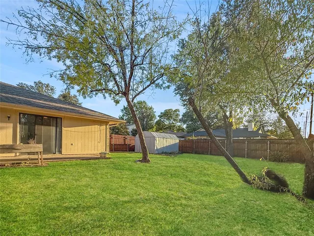 a view of a backyard with a garden and a tree