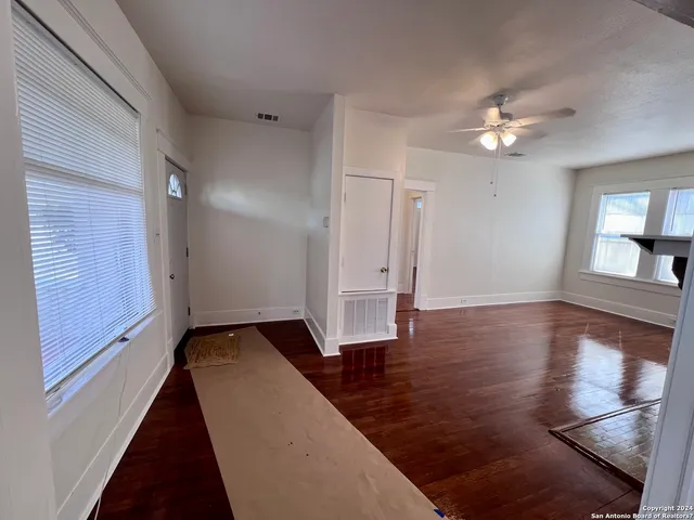 a view of an empty room with wooden floor and a window