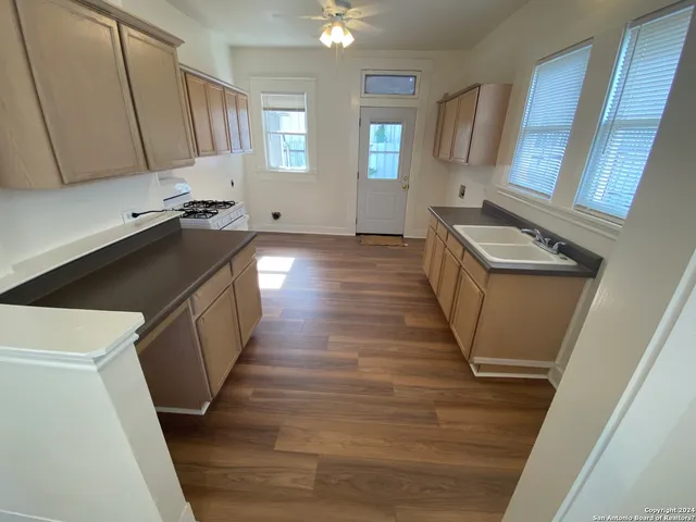 a kitchen with granite countertop a stove a sink and a refrigerator
