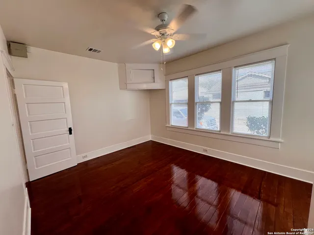 a view of an empty room with a window and wooden floor
