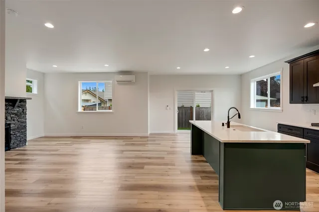 a kitchen with stainless steel appliances granite countertop a sink dishwasher a stove and a refrigerator with wooden floor