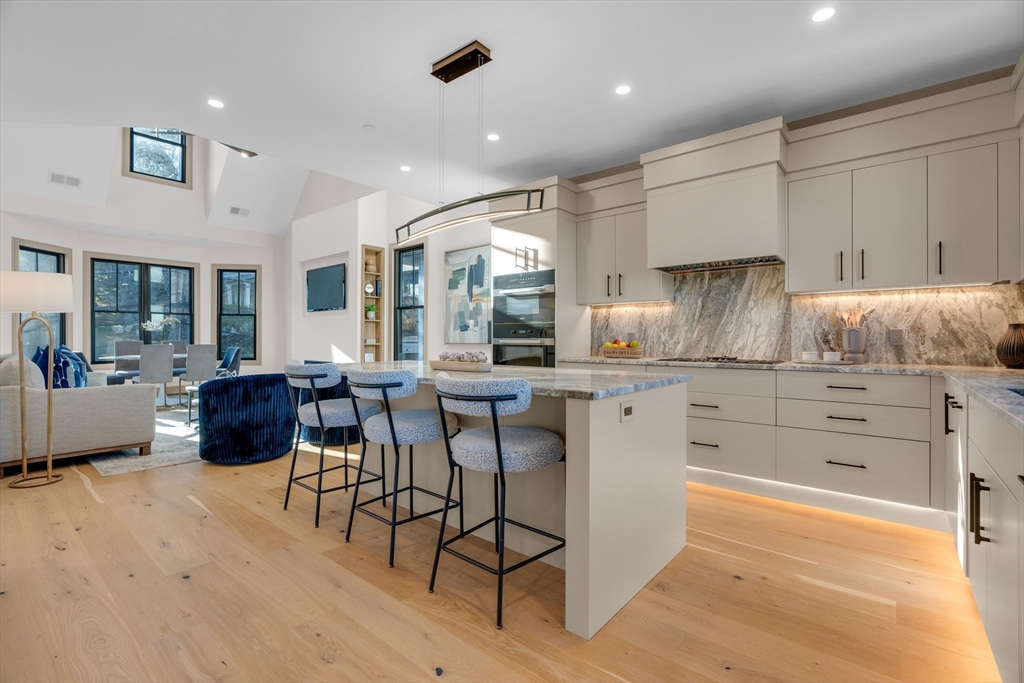 a kitchen with stainless steel appliances kitchen island granite countertop a stove a refrigerator and white cabinets with wooden floor