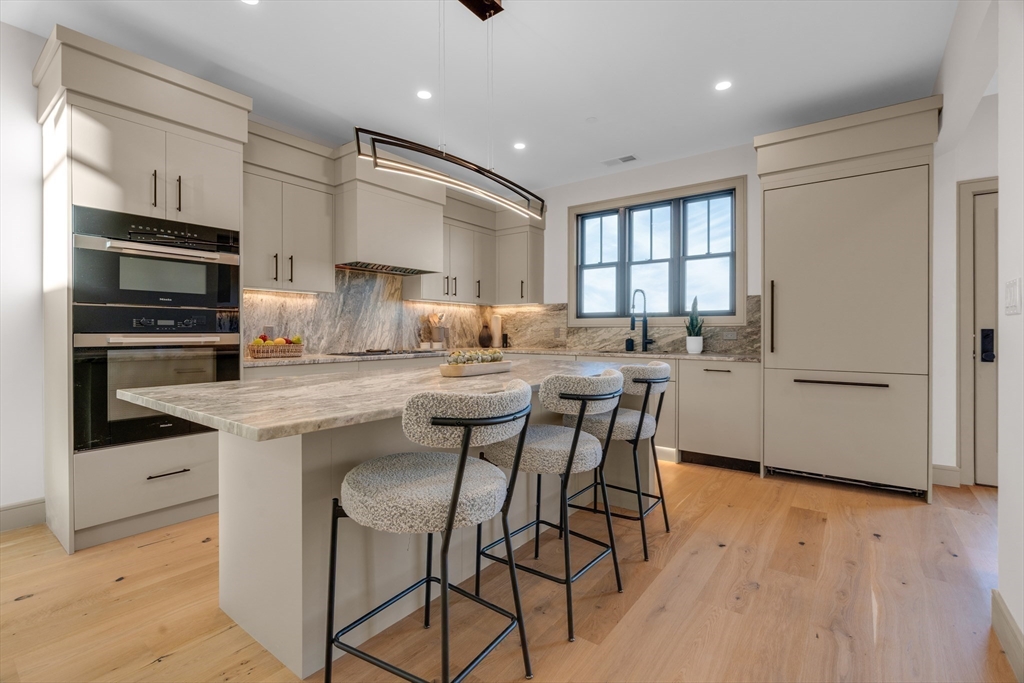 151 Mason Terrace, Unit 2 Brookline, MA 02446 - Photo 6 of 21 a kitchen with stainless steel appliances granite countertop a stove top oven a sink dishwasher and a refrigerator with wooden floor
