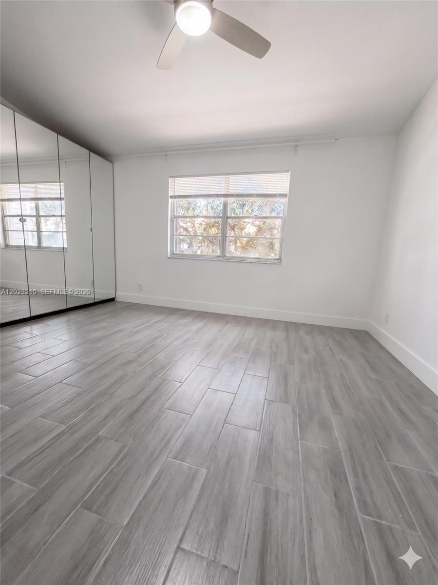 13 Southwest 3rd Street, Unit 13 Pompano Beach, FL 33060 - Photo 27 of 44 an empty room with wooden floor chandelier fan and windows