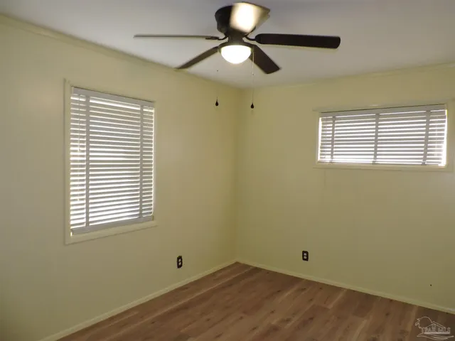 a view of empty room with wooden floor and fan