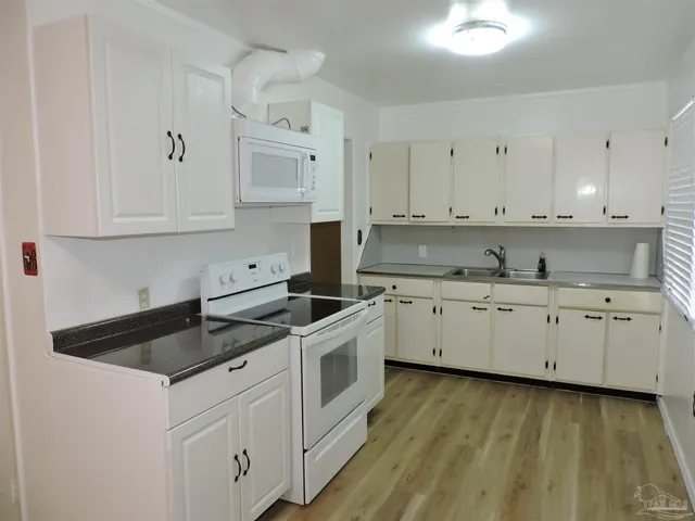 a kitchen with granite countertop white cabinets and white appliances
