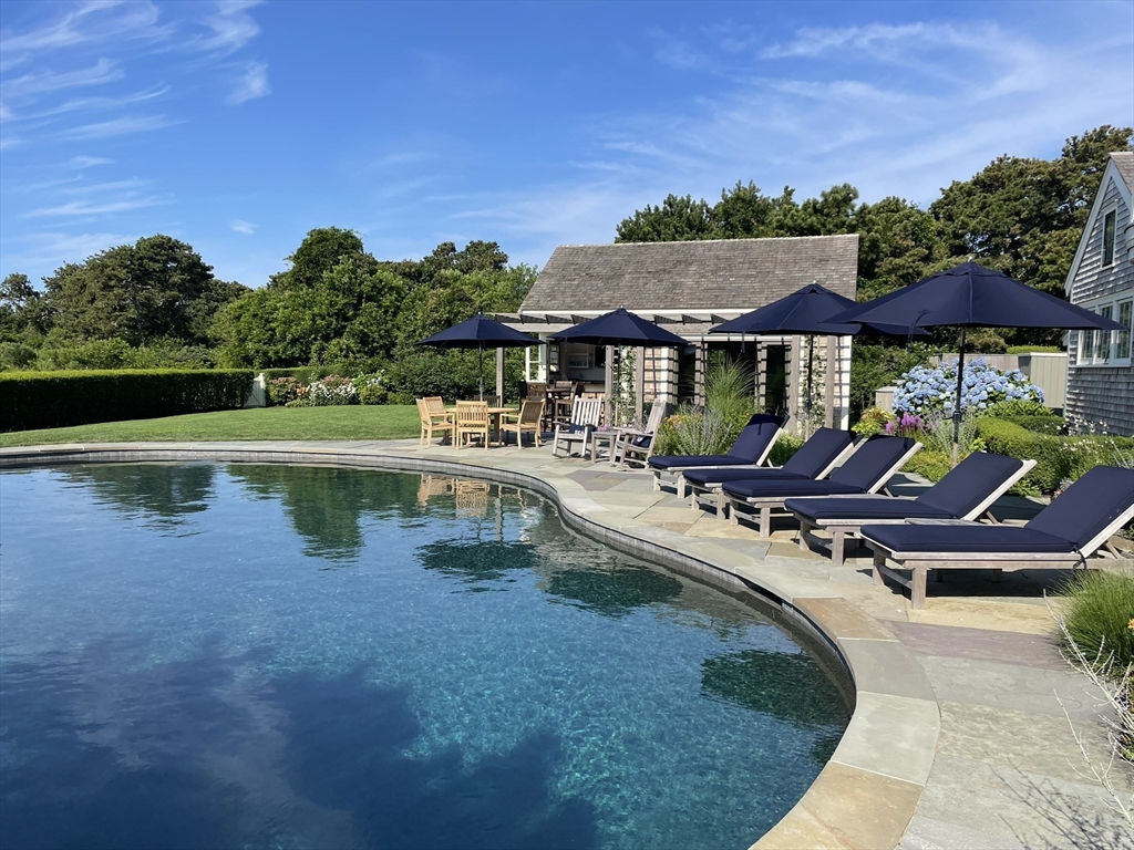 a view of pool with lawn chairs and plants