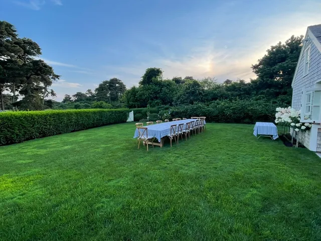 a backyard of a house with table and chairs plants and large trees