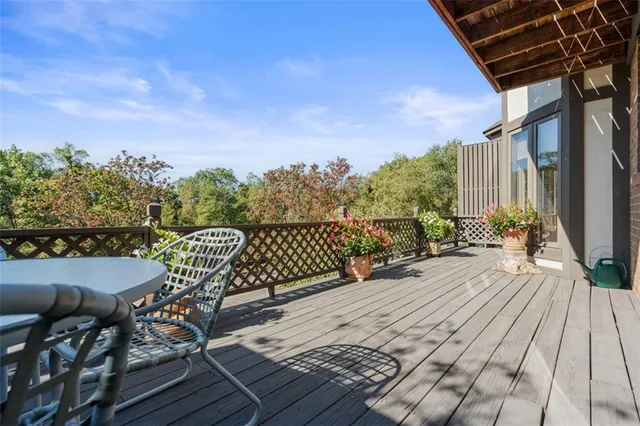 a view of a roof deck with table and chairs a barbeque with wooden floor and fence