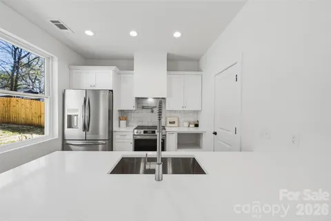 a kitchen with stainless steel appliances a sink a stove a refrigerator a window