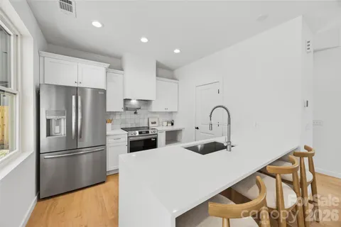 a kitchen with stainless steel appliances granite countertop a refrigerator sink and white cabinets