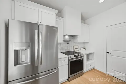 a kitchen with stainless steel appliances a refrigerator stove and white cabinets