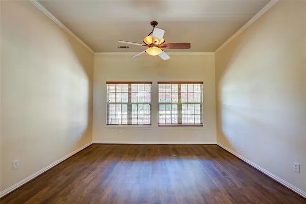 a view of an empty room with window and wooden floor