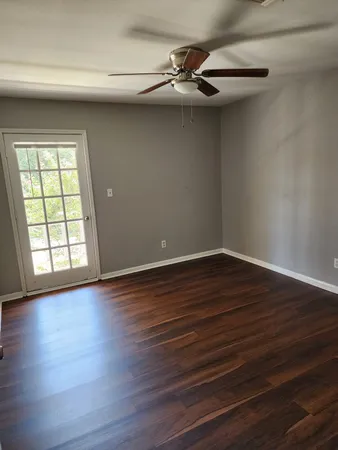 a view of an empty room with wooden floor and a window